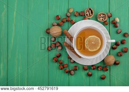 Top View Of Cup Of Hot Toddy With Lemon Inside And Cinnamon On Saucer With Pattern Of Nuts And Walnu