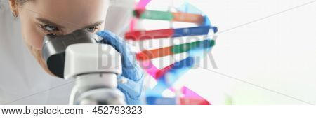Woman Scientist Looking Through Microscope Near Dna Molecule Mockup In Lab. Scientific Genetic Resea
