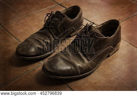 Used Untied Brown Leather Men Shoes Closeup On Tiled Floor In Grunge Style