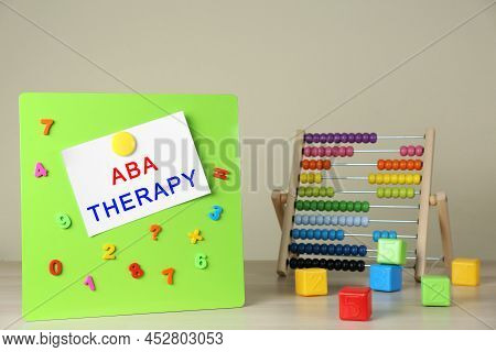 Magnetic Board With Phrase Aba Therapy, Colorful Numbers And Abacus On White Wooden Table