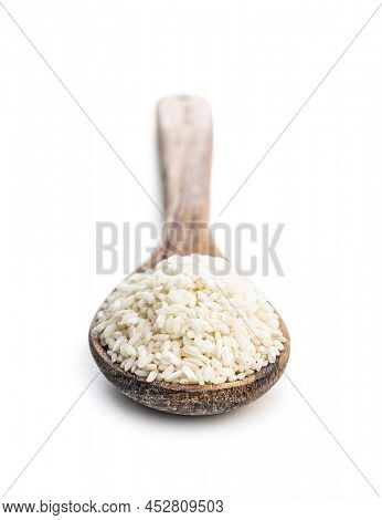 Uncooked Carnaroli risotto rice in wooden spoon isolated on a white background.