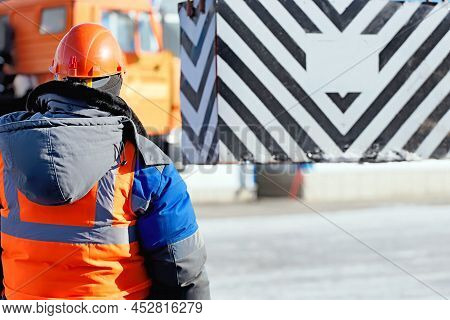Professional Slinger In Construction Helmet At Factory Unloads Cargo. Boot Training. Worker In Warm 