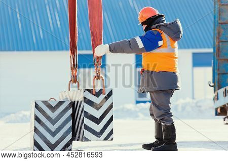 Professional Slinger In Construction Helmet At Factory Unloads Cargo. Boot Training. Worker In Warm 