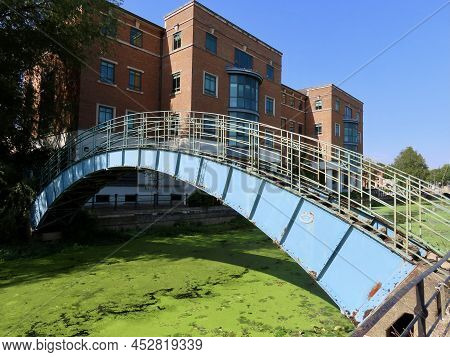 Blue Pedestrian Bridge Over Duckweed Covered River Foss In York, England. Health And Safety Executiv