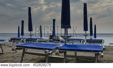 Deckchairs With Umbrellas On The Italian Beaches Of The Western Ligurian Riviera, In Spotorno, In Th