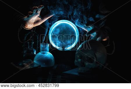 Close-up Of The Hands Of A Magician Telling The Future With A Blue Crystal Ball, Surrounded By Smoke