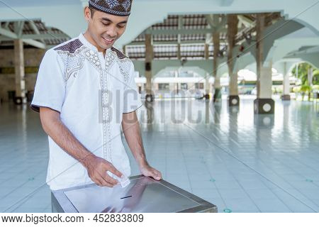 Muslim Paying Some Zakat Charity Using Cash At The Mosque