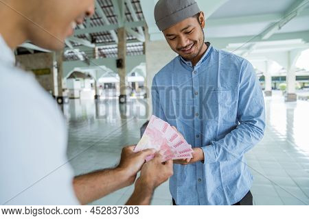 Muslim Paying Some Zakat Charity Using Cash At The Mosque