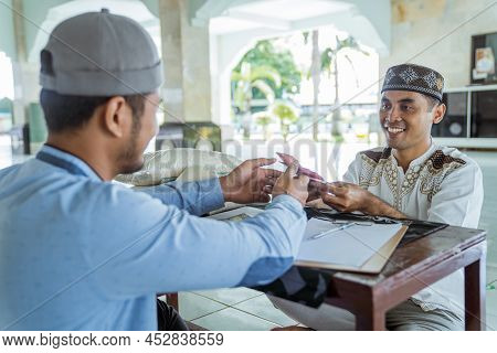 Muslim Paying Some Zakat Charity Using Cash At The Mosque