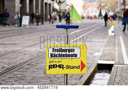 Freiburg, Germany - April 2022: Sign Pointing To Shop That Sells Small Wooden Toy Boats Children Can