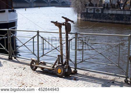 Two Drowned Electric Rent Scooters In The Mud Stand On The Citys Embankment. Vandals Throw Scooters 