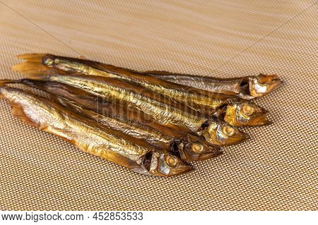 Smoked Capelin Against A Beige Background. Five Ready-to-eat Little Fish. Seafood.