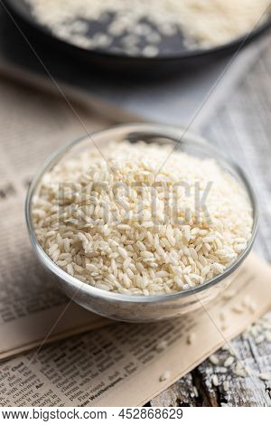 Uncooked Carnaroli risotto rice in a glass bowl.