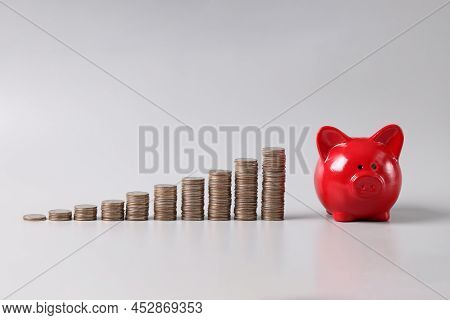 Close-up Of Stack Of Coins In Ascending Order And Red Piggy Bank On Table, Profitable Investment Of 