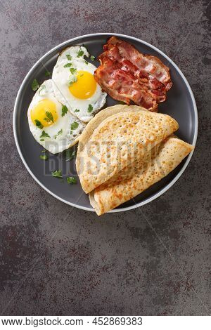 English Breakfast Of Bacon, Eggs And Oatcakes Oat Pancakes Close-up In A Plate On The Table. Vertica
