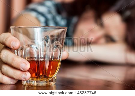 Donna ubriaca tenendo una bevanda alcolica e dormire con la testa sul tavolo (Focused on la bevanda