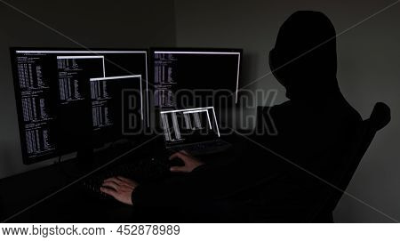 Hacker In The Dark Working On Multiple Devices