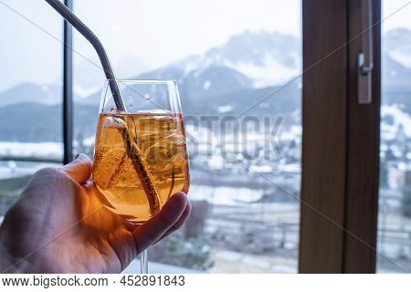 Close-up Of Hand Holding Drink Against Mountains At Resort During Winter