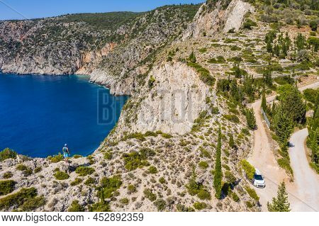 Aerial Photo Of Man Traveler On The Cliff Edge Of Beautiful And Picturesque Rocky Coast Close To Ass