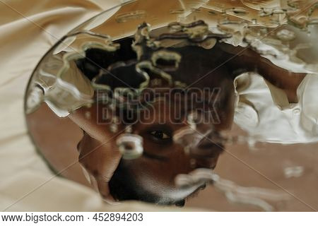 Close-up Of Reflection Of Young African Woman Looking Through Drops In Mirror
