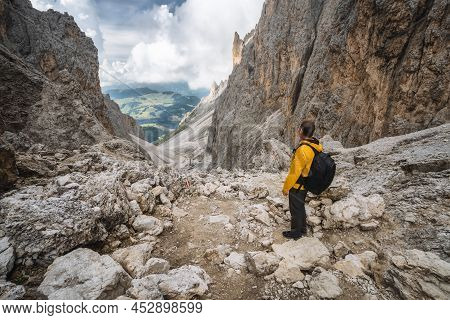 Man In Yellow Jacket And Backpack At Pass On Mountain Sassolungo - Langkofel, Alpe Di Siusi, Dolomit