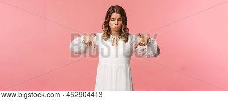 Gloomy, Jealous And Upset Cute Blond European Woman In White Trendy Spring Dress, Sulking As Pointin