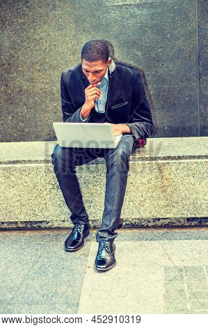 Young African American Man Wearing Black Blazer, Pants, Leather Shoes, Sitting On Marble Bench In Ne