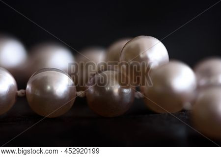 Close Up Pearls Bead On Black Paper Background. Soft Focus