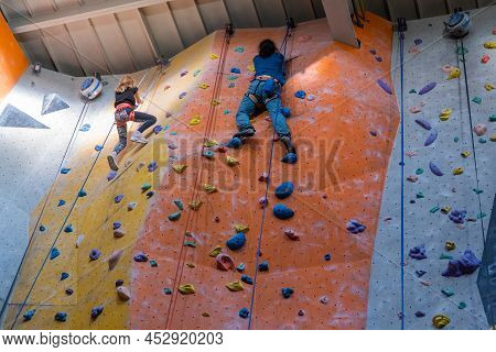 The Climbers Train On The Artificial Rock Wall With Insurance In Bouldering Gym, April 2022, Prague,