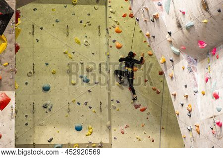 The Climber Trains On The Artificial Rock Wall With Insurance In Bouldering Gym, April 2022, Prague,