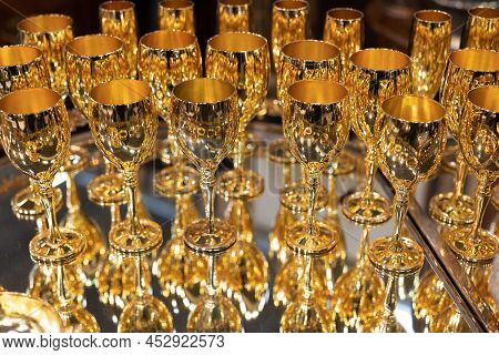Group Of Gilded Goblets Arranged Neatly On A Mirrored Tray With Reflection.