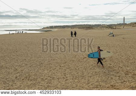 Man Walking To The Sea With His Surfboard At Los Canos De Meca On Spain