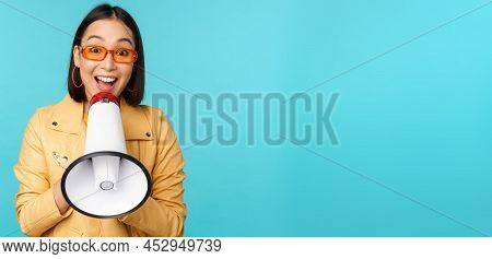 Stylish Asian Girl Making Announcement In Megaphone, Shouting With Speakerphone And Smiling, Invitin