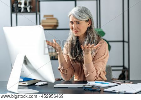 Confused Gray-haired Mature Lady, Business Woman Manager Or Consultant, Looking At The Computer In C