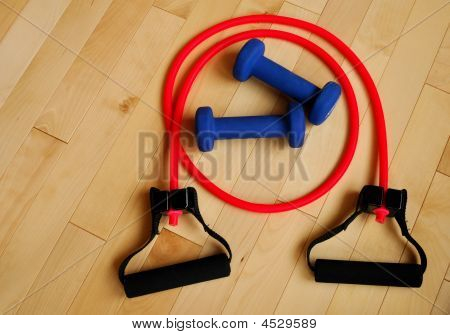 Red Resistance Band And Blue Weights On Gym Floor