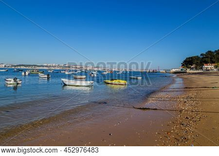 Trafaria, Portugal - March 1, 2022: Houses and bars along the seafront with wooden boats and pollutio at Trafaria, Portugal