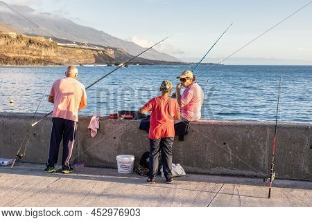 Tazacorte, Spain - March 02, 2022: Three People With Fishing-rods At Pier Near Harbor Tazacorte , La