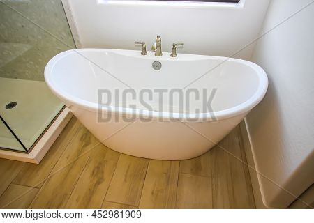 Free Standing White Oval Bath Tub In Master Bathroom