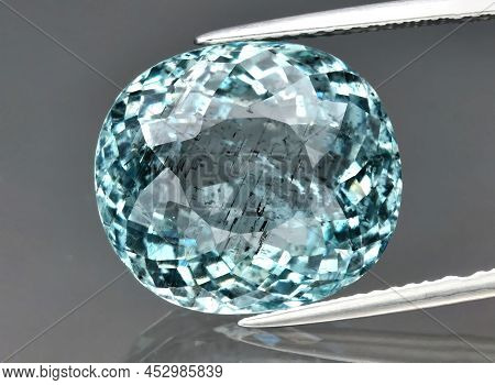 Natural Gemstone Blue Aquamarine In Tongs On A Gray Background