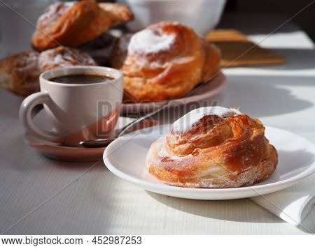 Breakfast With Fresh Pastries, A Cup Of Black Coffee, Cookies. Ensaimada On A Plate Close-up. Light 