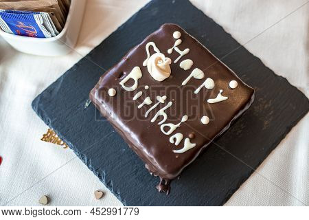 Iced And Decorated Chocolate Birthday Cake With Lettering Served On Table