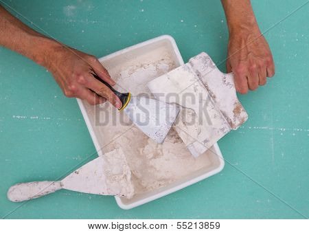 Plastering tools for plaster like plaste trowel spatula on green drywall plasterboard
