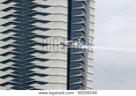 PUTRAJAYA, MALAYSIA - MAY 17, 2014: Matthias Dolderer of Germany, in an Edge 540 V3 plane flies by the skyscrapers of Putrajaya at the Red Bull Air Race World Championship 2014.
