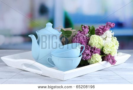 Composition with tea set and bouquet of beautiful spring flowers on tray, on wooden table, on bright background