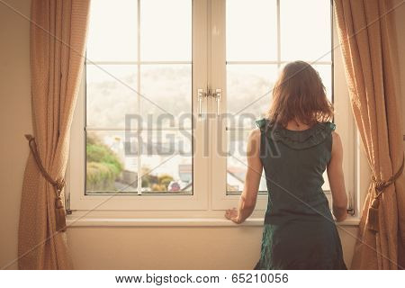 Young Woman In Dress Looking Out The Window