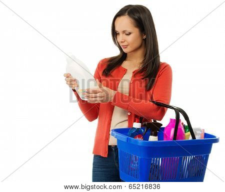 Beautiful brunette woman with basket reading label on cleanser 