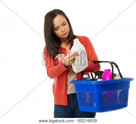 Beautiful brunette woman with basket reading label on cleanser 