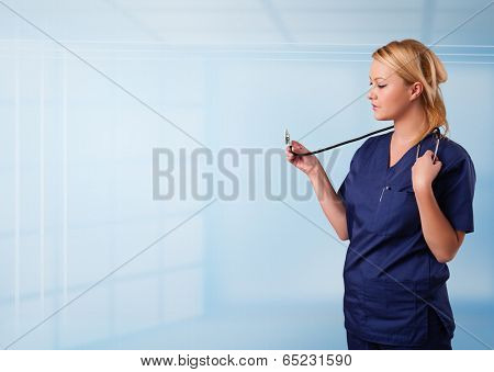 Pretty young nurse in hospital listening to empty copy space with sthetoscope
