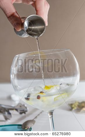 Barman pouring drink to prepare gin tonic cocktail