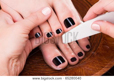 Pedicurist master makes pedicure on woman's legs - Spa treatment concept
